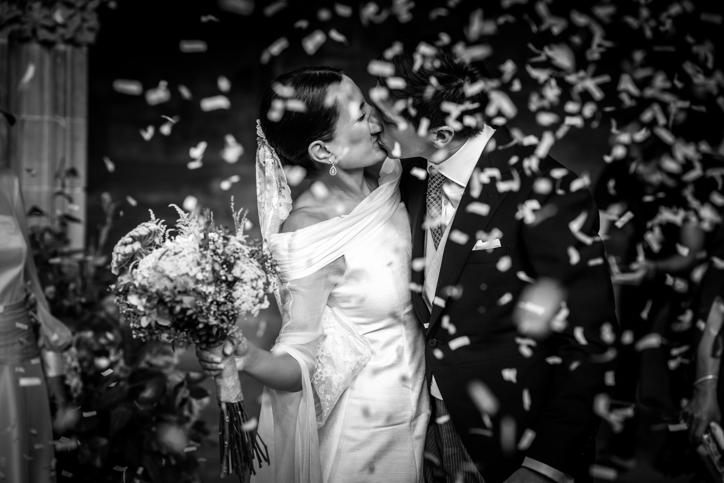 The newlyweds kiss in a storm of confetti at the monastery door of San Juan de la Peña
