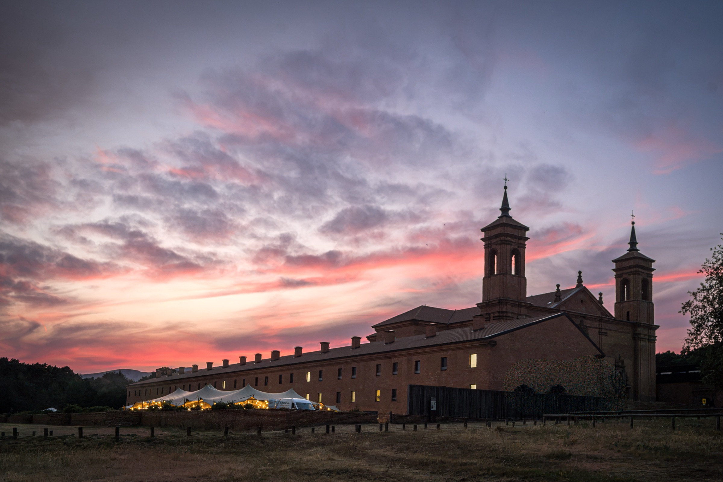 The new monastery of San Juan de la Peña at nightfall under a pink sky, the glowing reception marquee beneath its walls